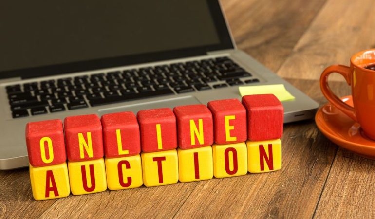 Träklossar med texten ONLINE AUCTION framför en laptop.